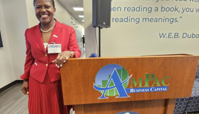 Hilda Kennedy, Founder and President of AmPac standing alongside the AmPac podium shortly after speaking to a room full of guests and supporters sharing key details of the merger and how excited she is to be able to boost the economic development in this region.